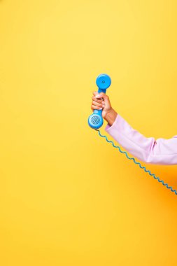 Sarıda mavi retro telefon tutan Afro-Amerikan kadın manzarası