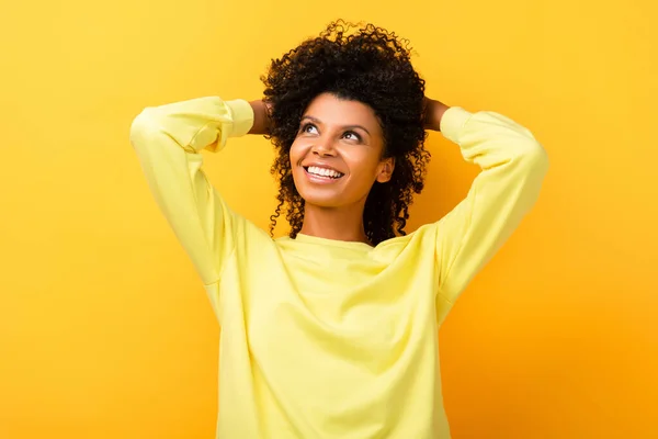 Happy African American Woman Looking Away While Fixing Curly Hair — Stock Photo, Image