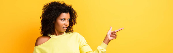 удивленный африканский американец женщина указывает пальцем на желтый, баннер