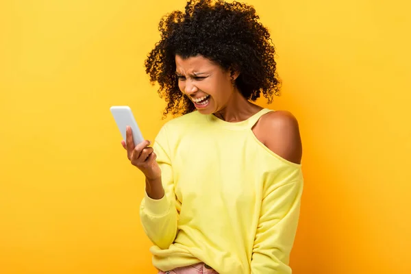 Upset African American Woman Holding Smartphone While Screaming Yellow — Stock Photo, Image
