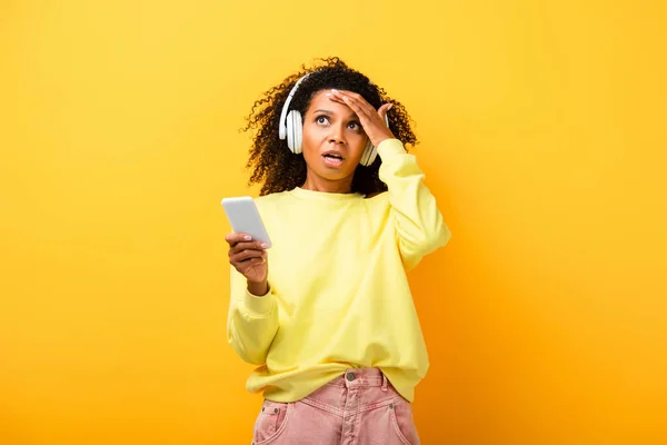 Confused African American Woman Headphones Holding Smartphone Yellow — Stock Photo, Image