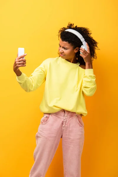 Mulher Afro Americana Insatisfeita Fones Ouvido Segurando Smartphone Amarelo — Fotografia de Stock