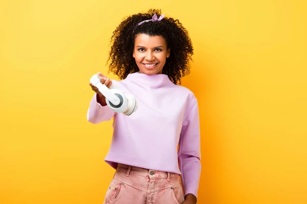 Mujer Afroamericana Feliz Sosteniendo Auriculares Inalámbricos Amarillo —  Fotos de Stock