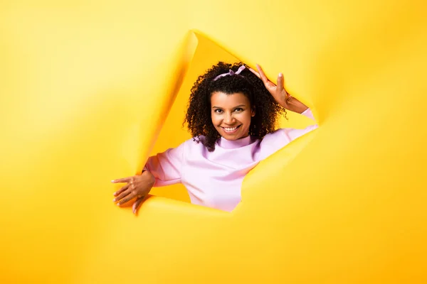 Happy African American Woman Looking Camera Hole Ripped Paper Yellow — Stock Photo, Image