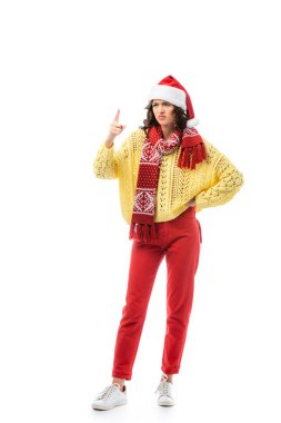 Noel Baba şapkalı ve eşarplı hoşnutsuz kadın elleri kalçasında ve parmaklarıyla beyazları işaret ediyor. 