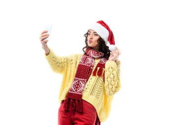Ördek yüzlü genç bir kadın, Noel Baba şapkası ve eşarbıyla beyaz telefondan selfie çekiyor. 