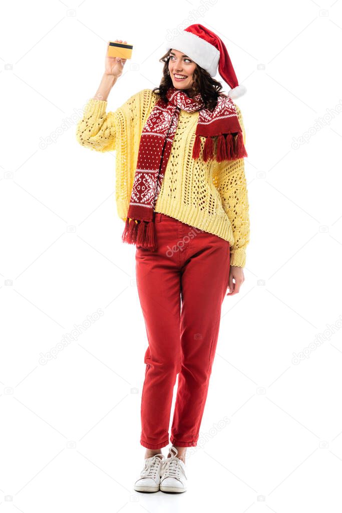 joyful woman in santa hat and scarf holding credit card isolated on white 