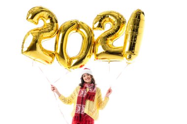 Noel Baba şapkalı ve atkılı neşeli genç kadın elinde balonlarla beyaz üzerinde 2021 numara izole edilmiş.