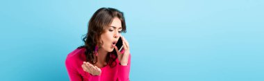 Akıllı telefonla konuşurken çığlık atan ve mavi ışıkta el kol gezen esmer kadının yatay mahsulü