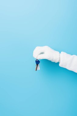 Kırpılmış beyaz eldivenli kadın görüntüsü mavi üzerinde anahtar taşıyor.