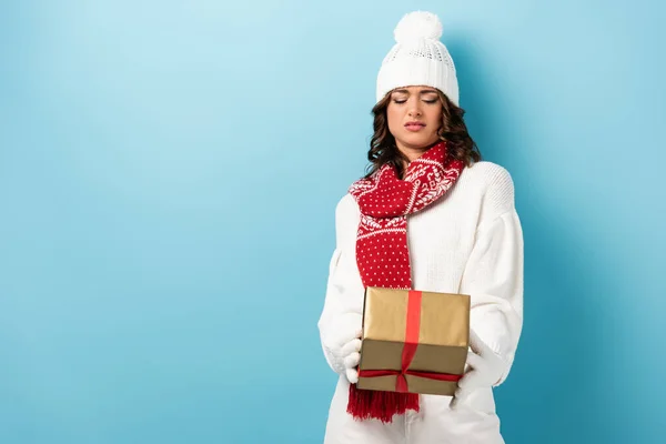 Mujer Escéptica Traje Invierno Mirando Regalo Envuelto Azul — Foto de Stock