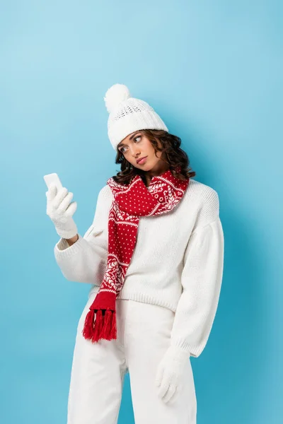 Nespokojená Žena Zimním Oblečení Při Pohledu Smartphone Gestikulace Modré — Stock fotografie