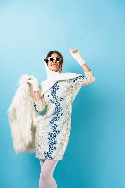 Joyful Woman Sunglasses Dress Holding Faux Fur Coat Gesturing Blue — Stock Photo, Image