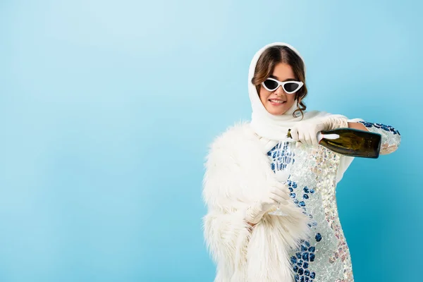 Pleased Woman Sunglasses Holding Bottle Pouring Champagne Glass Blue — Stock Photo, Image