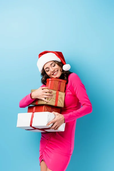 Jonge Vrolijke Vrouw Santa Hoed Jurk Omarmen Verpakt Geschenken Blauw — Stockfoto