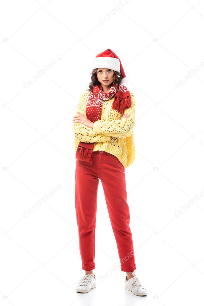 young brunette woman in santa hat and red scarf standing with crossed arms isolated on white 