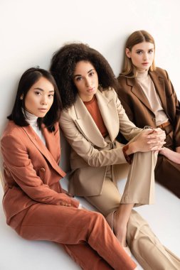 Çok kültürlü, modaya uygun takım elbiseli kadınların beyaz kameraya baktığı yüksek açılı manzara