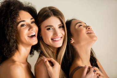 Genç çok kültürlü modeller kameraya bakıyor ve beyaza izole bir şekilde gülüyor. 