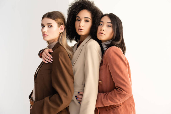 young interracial women in pastel formal wear posing on white