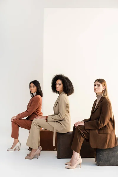 Full Length Multicultural Women Trendy Suits Sitting Baggage White — Stock Photo, Image