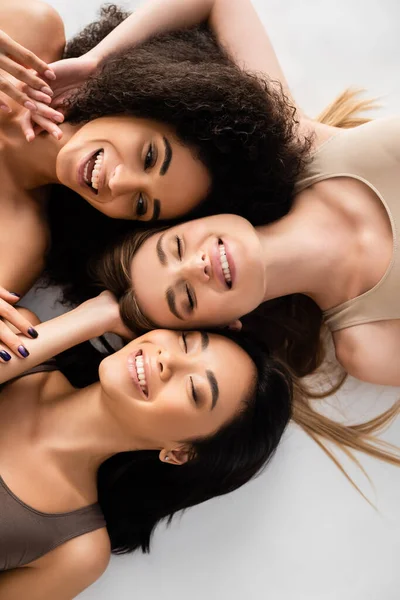Top Uitzicht Van Gelukkig Interraciale Vrouwen Lachen Terwijl Liggend Geïsoleerd — Stockfoto