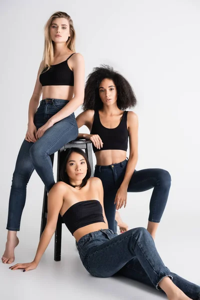 Trendige Interrassische Frauen Jeans Posieren Der Nähe Von Hockern Auf — Stockfoto