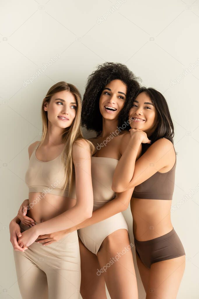 happy interracial models in underwear smiling while posing isolated on white