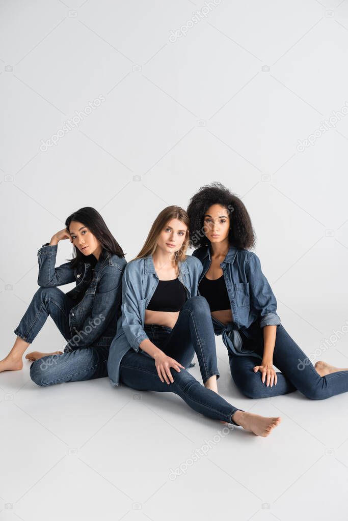 young interracial women in denim outfit posing on white