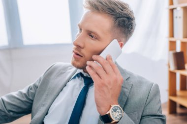 Resmi olarak genç işadamı ofiste akıllı telefondan konuşuyor. 