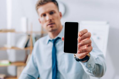 Bulanık arka planda iş adamının elinde boş ekranlı akıllı telefon. 