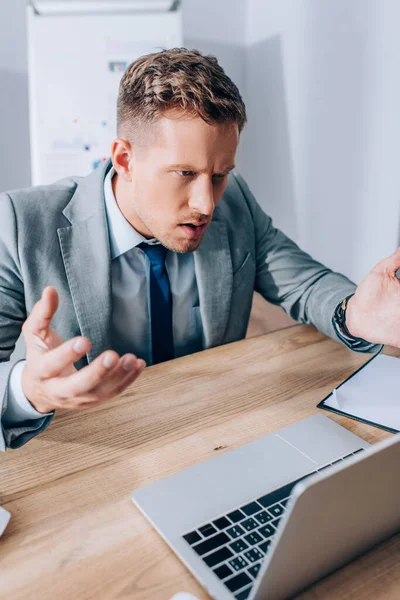 Zdezorientowany Biznesmen Patrząc Laptopa Zamazanym Pierwszym Planie Biurze — Zdjęcie stockowe