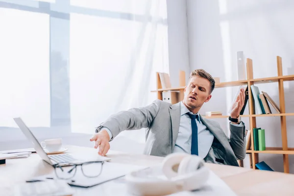 Embarrassed Businessman Pushing Back Laptop Headphones Eyeglasses Blurred Foreground Office — Stock Photo, Image