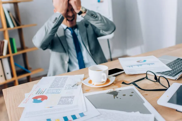 Koffie Gieten Buurt Van Papieren Apparaten Schreeuwende Zakenman Wazig Achtergrond — Stockfoto