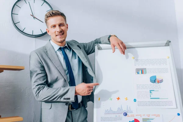 Lächelnder Geschäftsmann Zeigt Büro Auf Papiere Mit Grafiken Auf Flipchart — Stockfoto