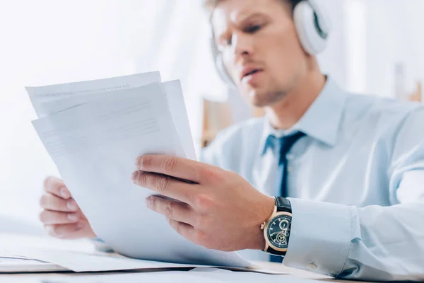 黒ずみの背景にヘッドフォンで音楽を聞くビジネスマンの手の中の文書 — ストック写真
