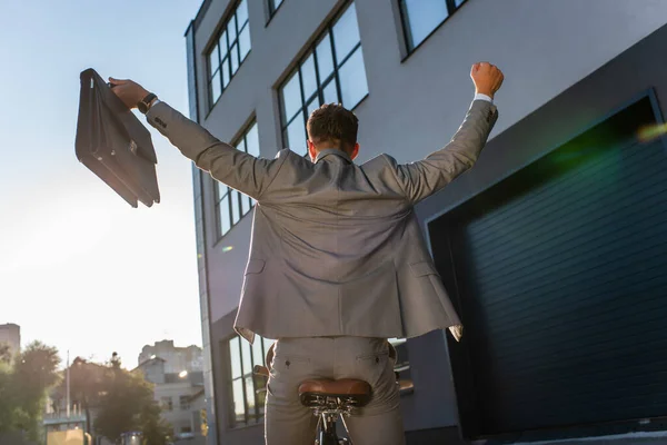 Back View Businessman Showing Yeah Gesture While Holding Briefcase Cycling — Stock Photo, Image