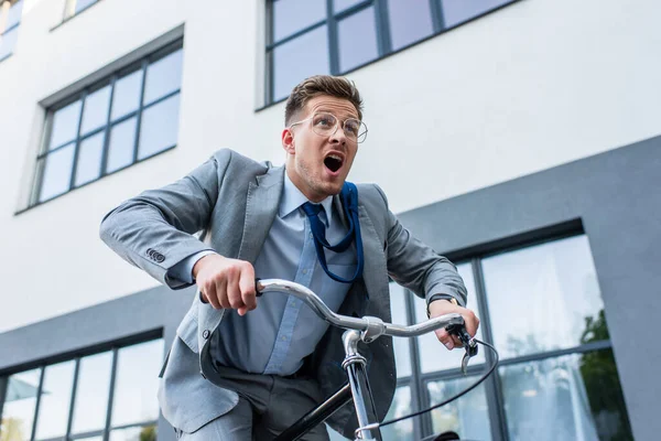 Excited businessman cycling near building outdoors