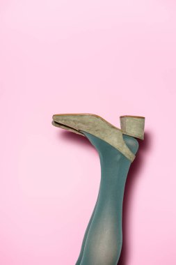 Yeşil taytlı kadın bacağı ve leylak arka planda retro ayakkabılar.