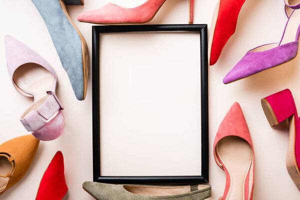 top view of heeled shoes and empty frame on white background