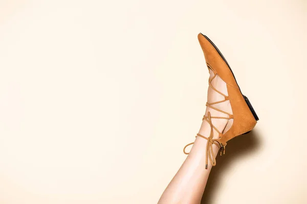 Kahverengi Süet Ayakkabılı Bej Arka Planda Kadın Bacağı — Stok fotoğraf
