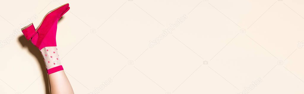 cropped view of female leg in pink retro socks and shoes on beige background, banner