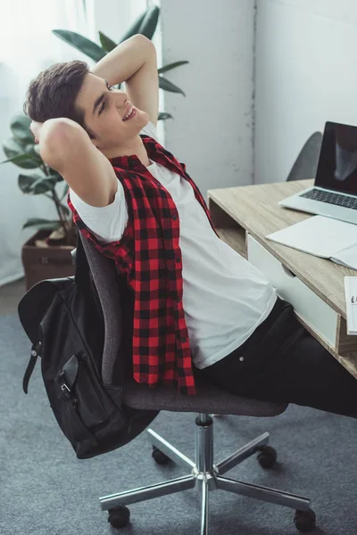 Estudiante masculino descansando después de hacer la tarea con el ordenador portátil y los copybooks en el país - foto de stock