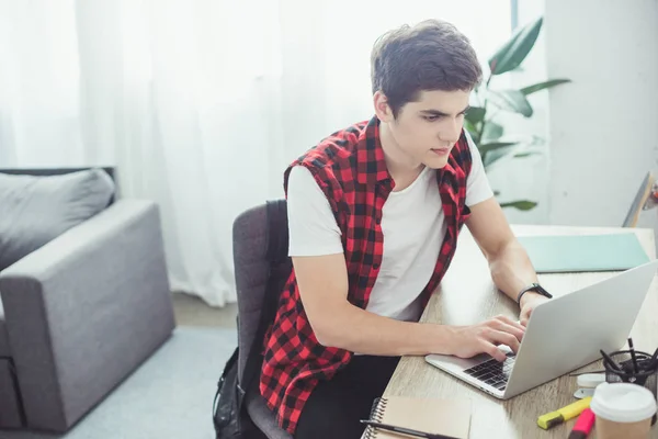 Mâle caucasien étudiant tapant sur ordinateur portable à la maison — Photo de stock
