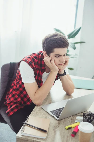 Studente maschio pensieroso che fa guardando computer portatile — Foto stock