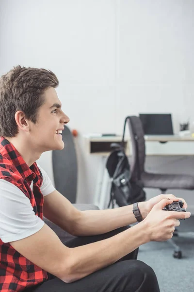 Smiling teenager playing video game with joystick at home — Stock Photo