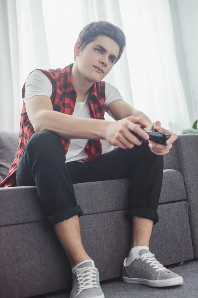 Bored teen boy playing video game with joystick at home — Stock Photo