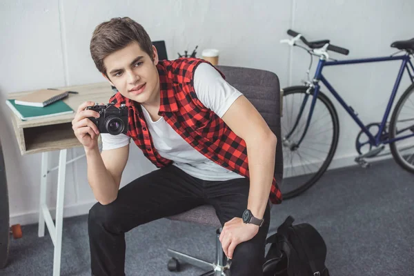 Adolescente com câmera de filme sentado em casa com bicicleta atrás — Fotografia de Stock