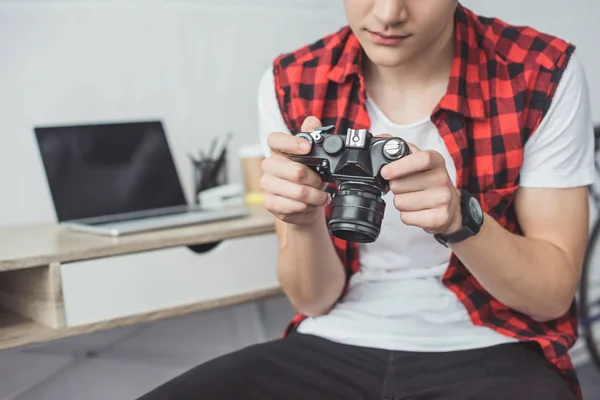 Cropped view of teenager with retro film camera sitting at home — Stock Photo