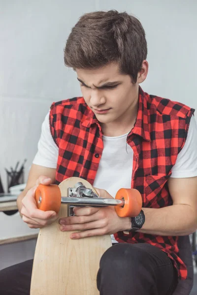 Jovem skatista reparar seu longboard em casa — Fotografia de Stock