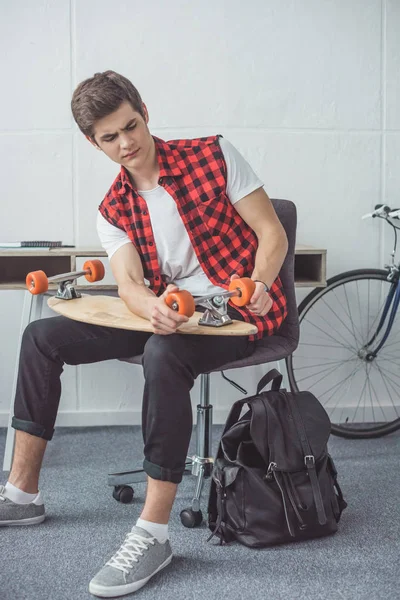 Junger Skateboarder repariert sein Longboard zu Hause — Stockfoto